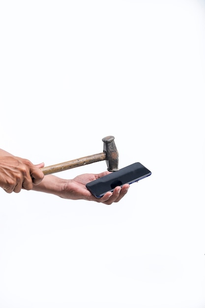 Foto un hombre está rompiendo un teléfono inteligente con un gran martillo.