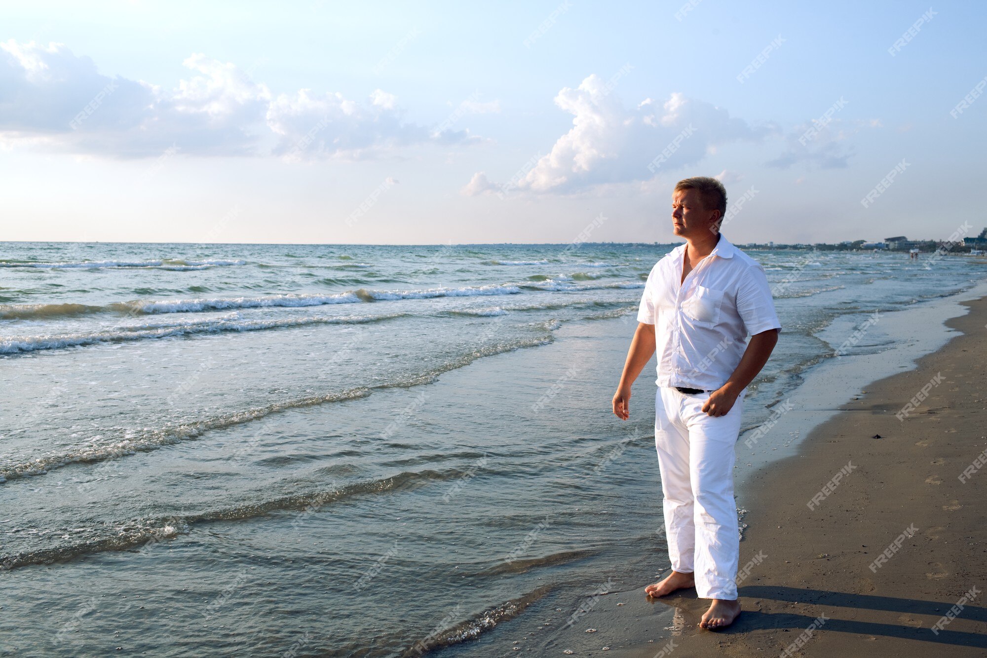 Hombre en ropa blanca en la playa del mar Foto