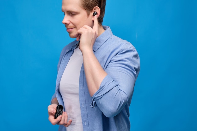 El hombre con ropa casual en azul cambia la canción presionando el auricular inalámbrico en su oído.