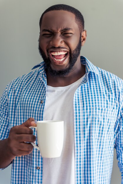 Hombre en ropa casual elegante está sosteniendo la taza y gritando