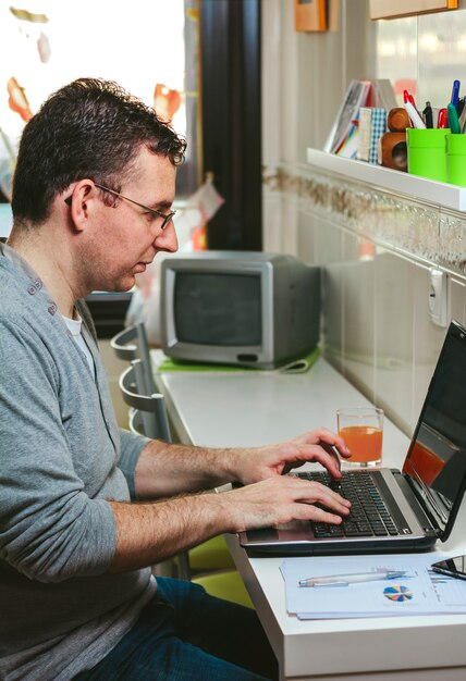 Hombre con ropa casual trabajando desde casa con portátil