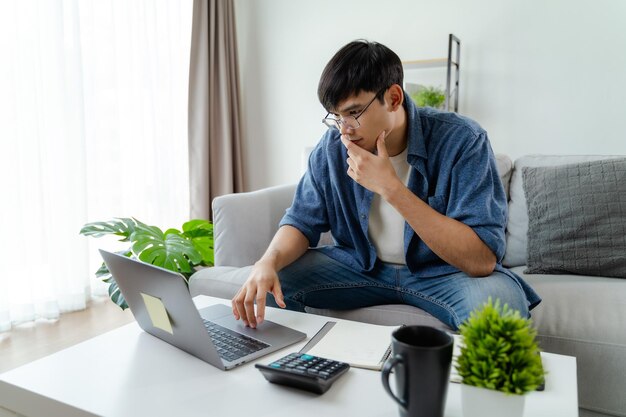 Foto el hombre con ropa casual trabajando con una computadora portátil calculadora de teléfono inteligente