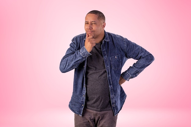 Hombre en ropa corta con camisa vaquera, camiseta blanca y pantalón marrón en foto de estudio sobre un fondo con luces.