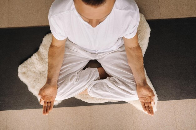 Un hombre con ropa deportiva blanca está haciendo yoga con un gimnasio, el concepto de un estilo de vida saludable