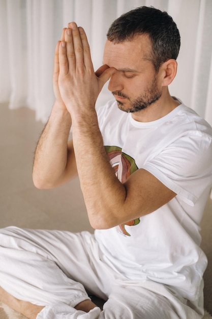 Un hombre con ropa deportiva blanca está haciendo yoga con un gimnasio, el concepto de un estilo de vida saludable