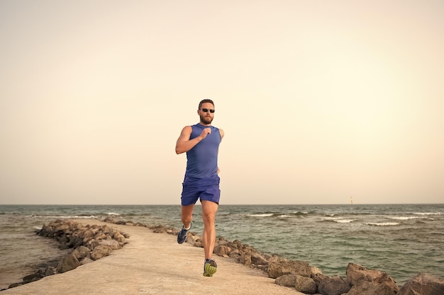 Hombre en ropa deportiva corriendo en la costa del mar éxito futuro corredor exitoso actividad de verano deporte recreación estilo de vida saludable correr para el éxito Hacia prácticas de éxito deporte correr de por vida