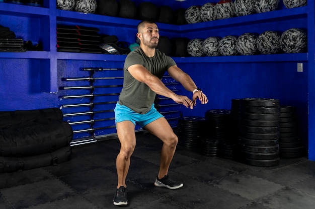 Hombre en ropa deportiva haciendo sentadillas en un gimnasio crossfit