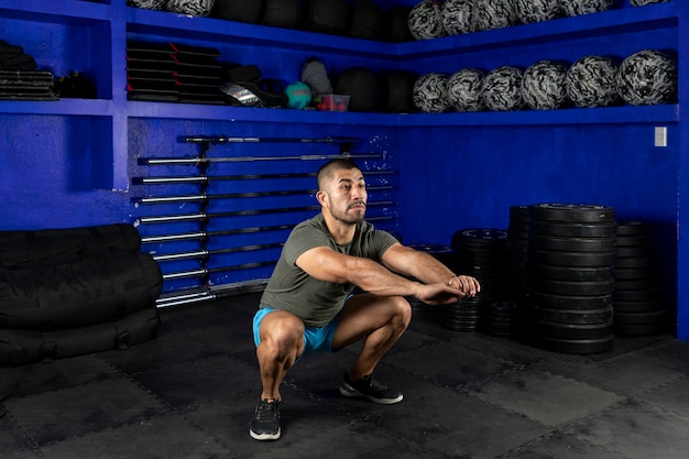 Hombre en ropa deportiva haciendo sentadillas en un gimnasio crossfit