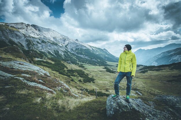 Hombre en ropa deportiva y con mochila disfruta de la vista en las montañas