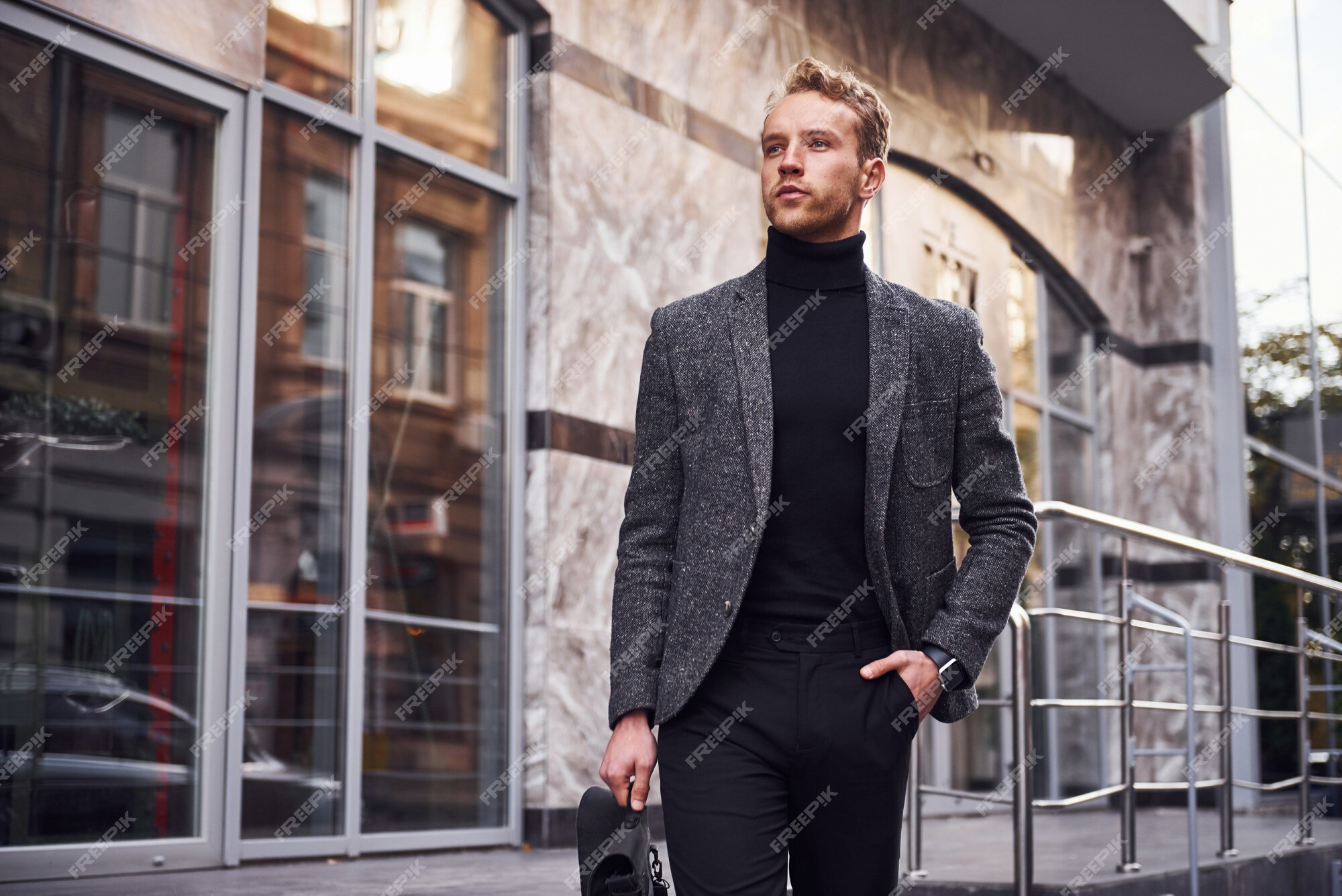 El hombre con ropa formal elegante y con está afuera contra el edificio moderno. |