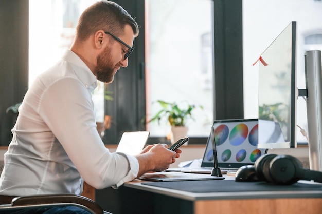 El hombre con ropa formal está trabajando en la oficina moderna usando la computadora