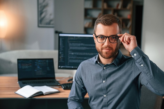 El hombre con ropa formal está trabajando en la oficina moderna usando la computadora