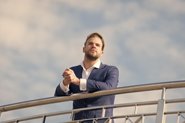 Hombre en ropa formal de pie en el cielo azul nublado Empresario confiado al aire libre Mirando hacia el futuro Pensando en nuevas posibilidades Look de moda masculina El mejor gerente de la historia Confianza y carisma