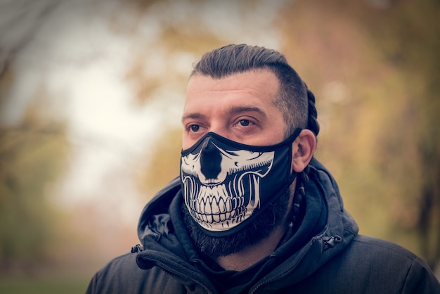 Hombre en ropa de invierno en la calle con una mascarilla médica. macho en un respirador para protegerse contra infecciones