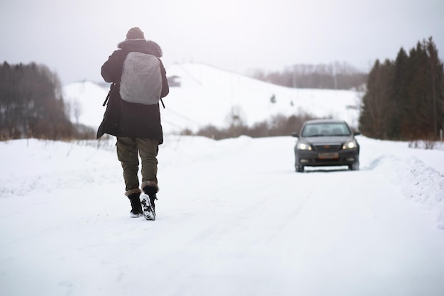 Un hombre con ropa de invierno en la calle Los turistas viajan por el país nevado En el camino caminan y hacen autostop