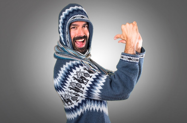 Hombre con ropa de invierno orgulloso de sí mismo sobre fondo gris