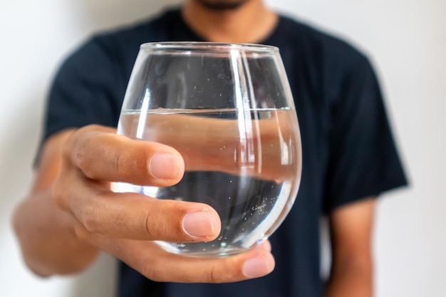 Un hombre con ropa negra sosteniendo un vaso de agua