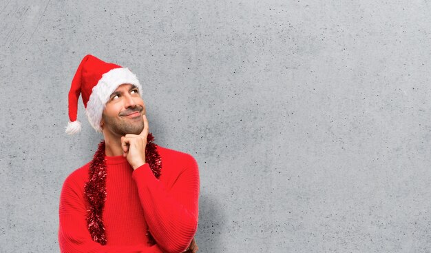 Hombre con ropa roja celebrando las vacaciones de Navidad de pie y pensando una idea