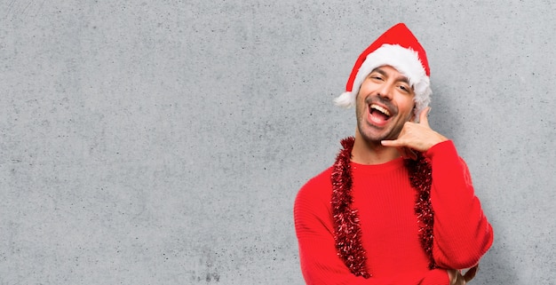 Foto hombre con ropa roja que celebra los días de fiesta de la navidad que hacen gesto del teléfono.
