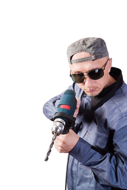 Hombre en ropa de trabajo gafas oscuras y gorra con taladro eléctrico hombre de mediana edad