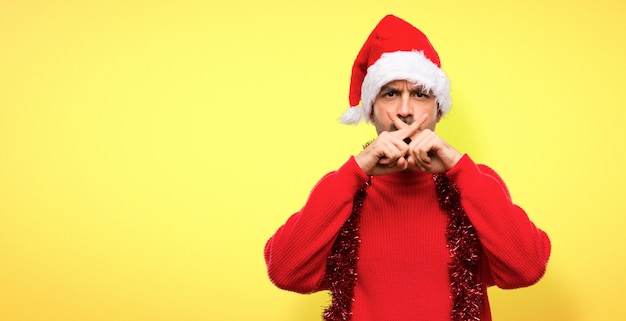 Hombre con ropas rojas celebrando las fiestas navideñas mostrando un gesto de silencio.