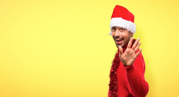 Hombre con ropas rojas celebrando las fiestas navideñas saludando con la mano.