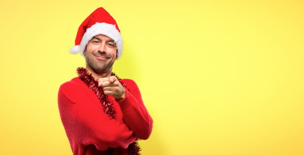 Hombre con ropas rojas celebrando las fiestas navideñas señala con el dedo a ti