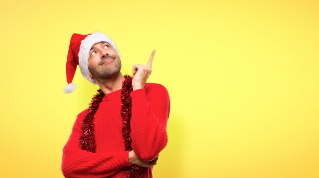 Hombre con ropas rojas celebrando las fiestas navideñas señalando una gran idea.