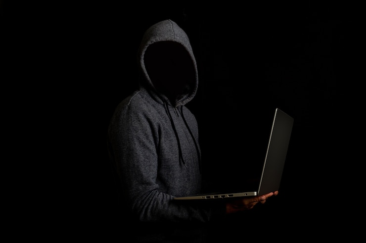 Foto el hombre sin rostro en una campana sostiene una computadora portátil en una oscuridad