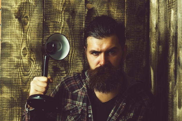 Hombre con rostro serio sosteniendo lámpara eléctrica