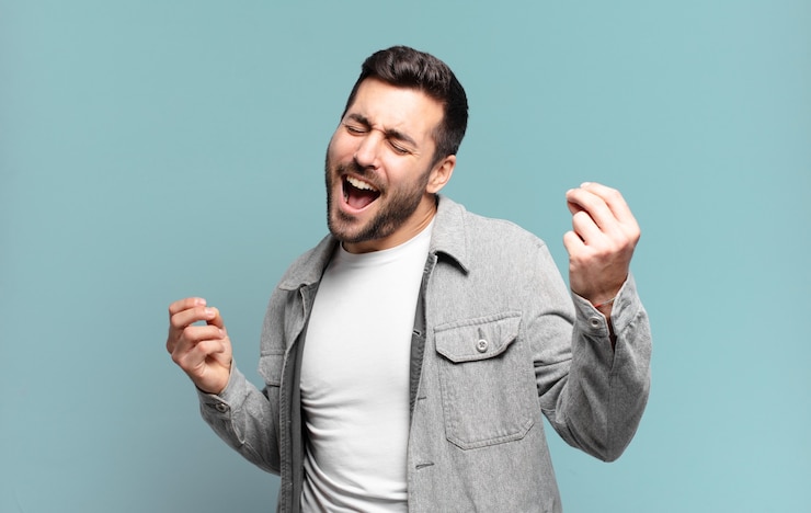 Foto hombre rubio adulto guapo sonriendo, sintiéndose despreocupado, relajado y feliz, bailando y escuchando música, divirtiéndose en una fiesta