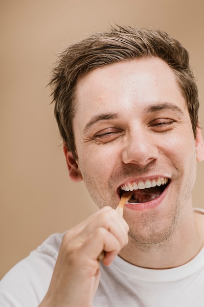 Hombre rubio cepillarse los dientes con un cepillo de dientes de madera