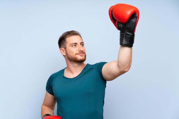 Hombre rubio deporte sobre pared azul con guantes de boxeo