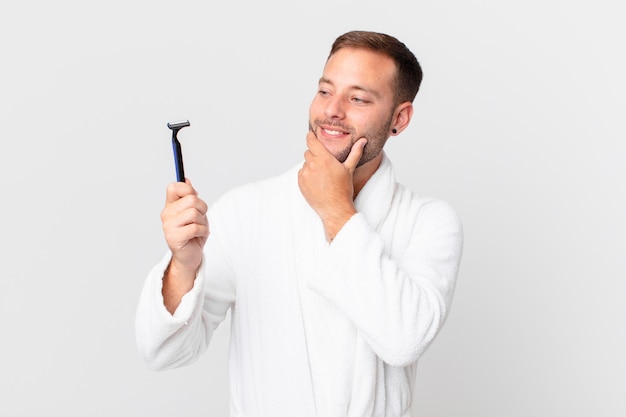 Hombre rubio guapo sonriendo con una expresión feliz y segura con la mano en la barbilla. concepto de afeitado