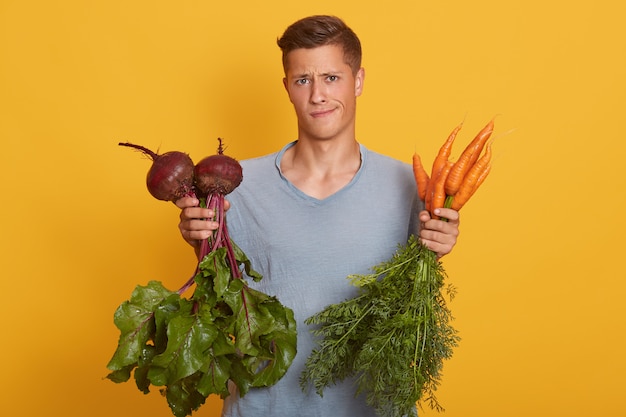 Hombre rubio hermoso que sostiene verduras frescas en manos