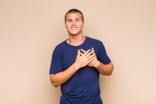 Hombre rubio que se siente romántico, feliz y enamorado, sonriendo alegremente y tomados de la mano cerca del corazón