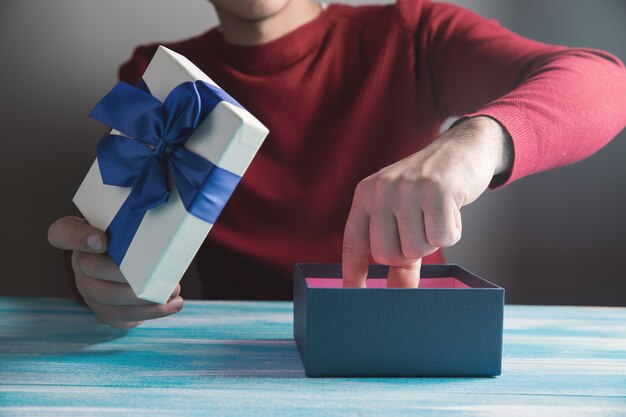 El hombre saca un regalo de la caja sobre la mesa