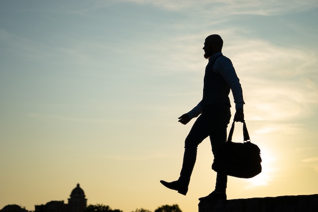 Hombre saliendo del borde durante la puesta de sol en el cielo. Concepto de riesgo y elección.