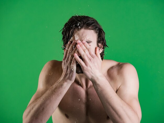 El hombre salpica agua en la cara sobre fondo verde