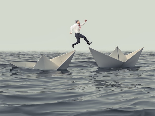 El hombre salta de un barco de papel que se hunde a uno flotante.