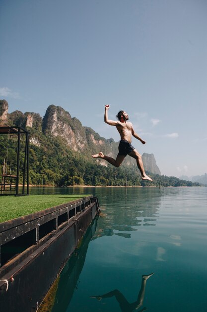 Hombre saltando de alegría por un lago