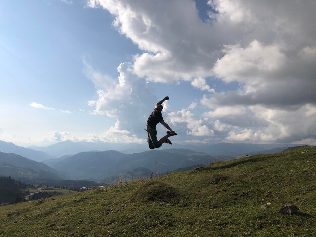 Hombre saltando en la montaña contra el cielo