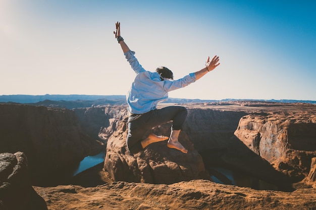Hombre saltando en roca por montaña contra el cielo