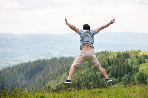 Un hombre en un salto en la cima de una montaña.