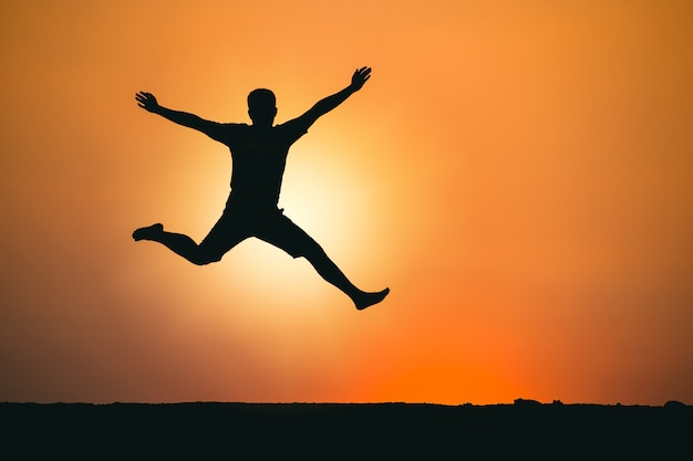 Foto el hombre saltó felizmente sobre el fondo del atardecer del concepto de negocio