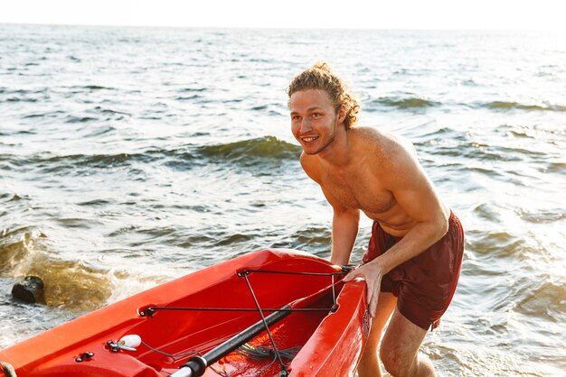 Hombre sano en forma en un kayak en el océano, lanzando un barco