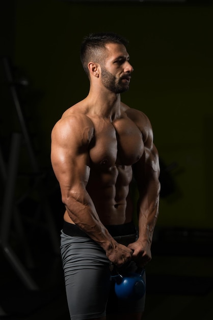 Hombre sano haciendo ejercicio con Kettle Bell y flexionando los músculos Muscular culturista atlético Ejercicios de modelo de fitness