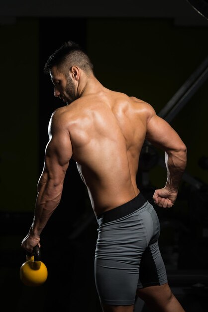 Hombre sano haciendo ejercicio con Kettle Bell y flexionando los músculos Muscular culturista atlético Ejercicios de modelo de fitness