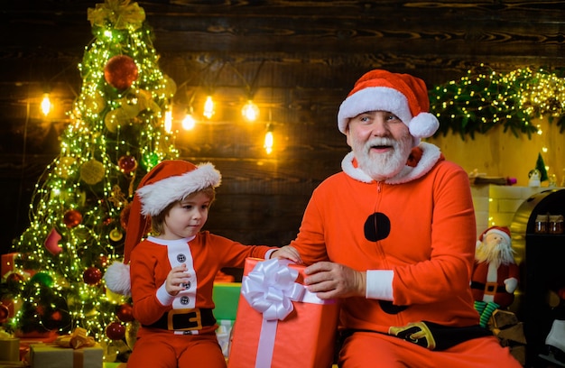 Hombre de santa claus y niño de santa en casa regalo de navidad concepto de vacaciones en familia sonriendo poco