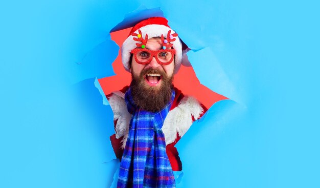 Hombre de santa en gafas de fiesta mirando a través de papel descuento navidad o ventas de año nuevo viernes negro